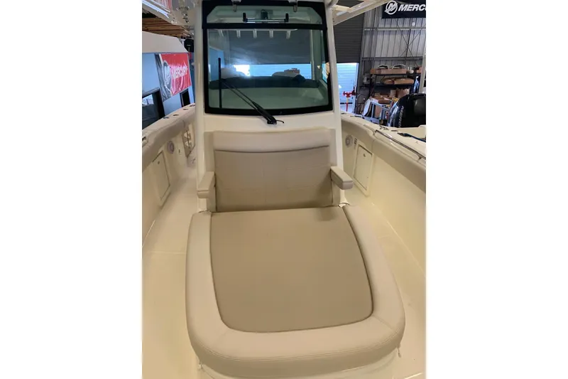 Slide: The Image of 2019 Boston Whaler 330 Outrage boat interior with cushioned seating and windshield. - 2