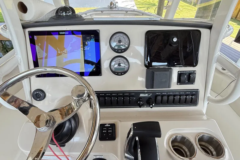 Slide: The Image of 2023 Boston Whaler 230 Outrage dashboard with steering wheel, navigation screen, and controls. - 1