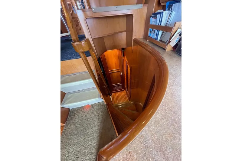 Slide: The Image of Staircase inside 1990 Offshore Yachts 55 Pilothouse, featuring wooden interior and bookshelves. - 16