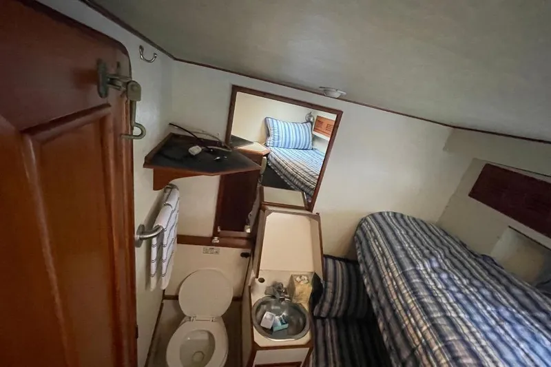 Slide: The Image of 1990 Offshore Yachts 55 Pilothouse interior with bathroom and striped bedding. - 23