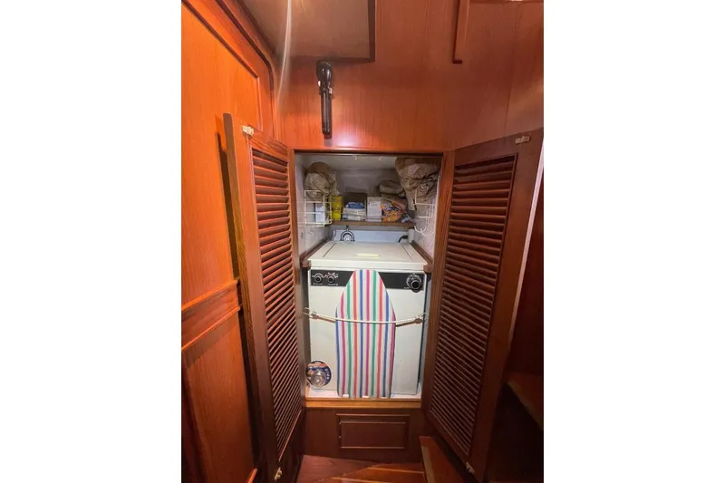 Slide: The Image of Laundry area in 1990 Offshore Yachts 55 Pilothouse with wooden cabinetry and storage shelves. - 24