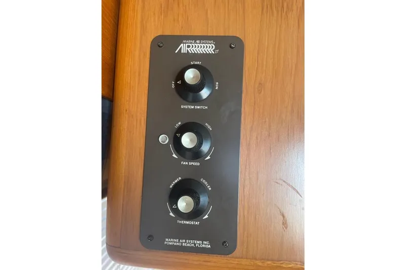 Slide: The Image of Control panel of a 1990 Offshore Yachts 55 Pilothouse, featuring system switch, fan speed, and thermostat. - 28