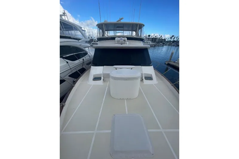 Slide: The Image of 1990 Offshore Yachts 55 Pilothouse on calm marina waters, showcasing spacious deck. - 29