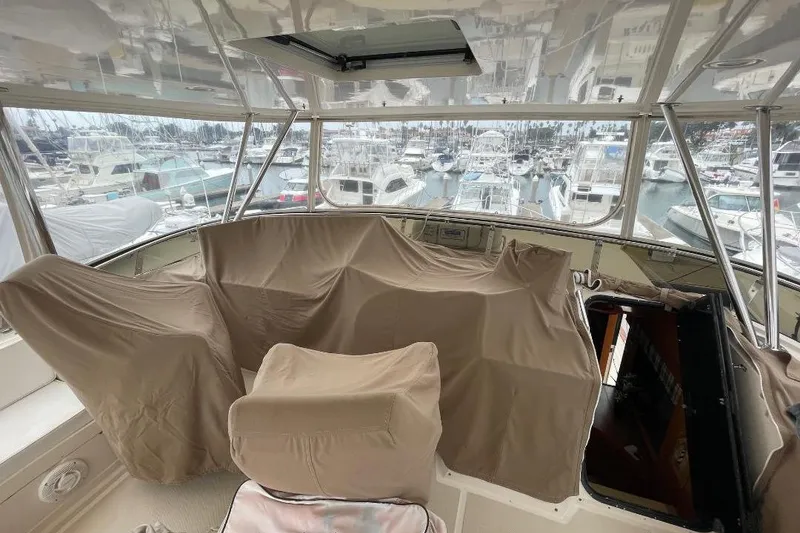Slide: The Image of 1990 Offshore Yachts 55 Pilothouse interior with covered seating, overlooking marina. - 33