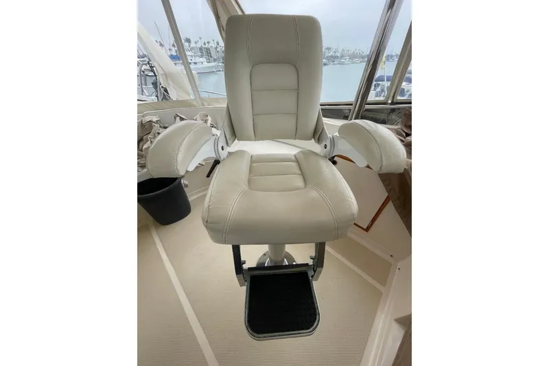 Slide: The Image of Captain's chair on 1990 Offshore Yachts 55 Pilothouse, featuring plush white upholstery. - 34