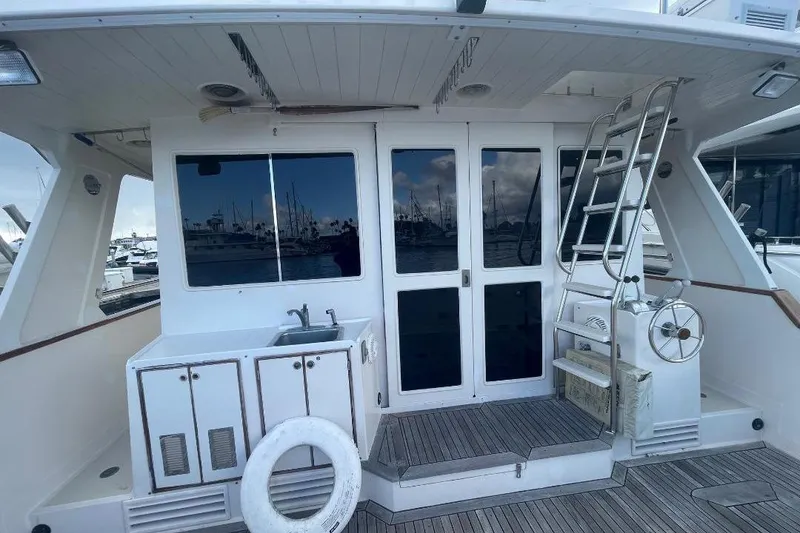 Slide: The Image of 1990 Offshore Yachts 55 Pilothouse deck with sink, ladder, and marina view. - 57