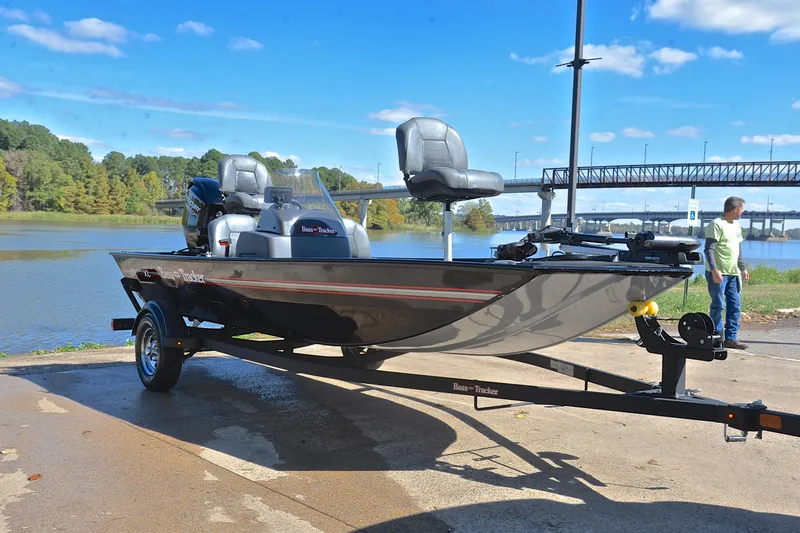 Slide: The Image of 2024 Bass Tracker Classic boat on trailer by a lake, under a clear blue sky. - 16