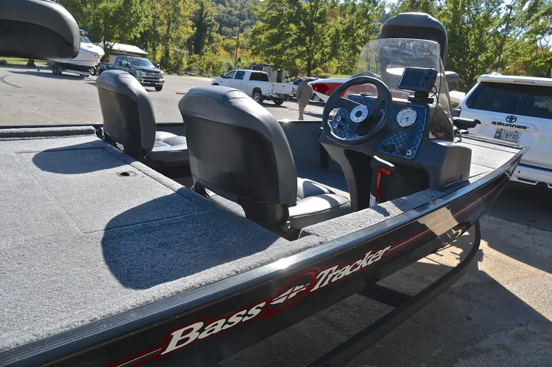 Slide: The Image of 2024 Bass Tracker Classic boat with dual seats and steering console in a parking area. - 19