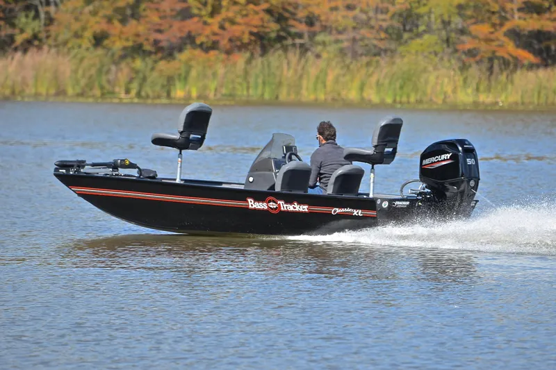 Slide: The Image of 2024 Bass Tracker Classic boat cruising on a lake with autumn foliage in the background. - 4