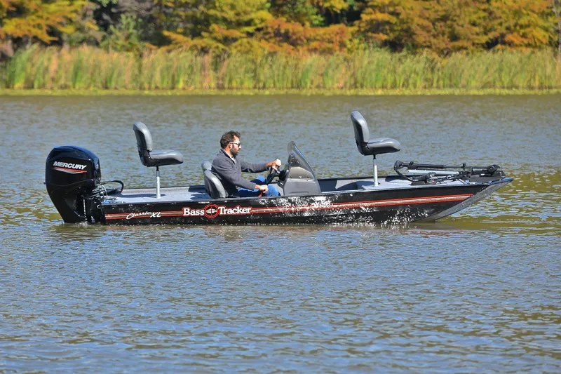 Slide: The Image of 2024 Bass Tracker Classic boat on a lake with a person driving. - 7