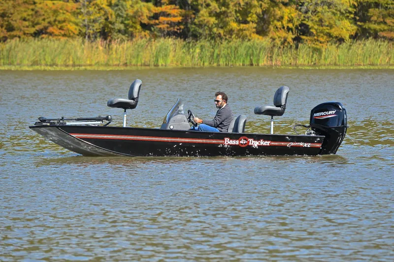 Slide: The Image of 2024 Bass Tracker Classic boat on a lake with a person driving. - 9