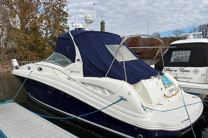 The Image of 2005 Sea Ray 340 Sundancer docked, featuring a blue canopy and sleek design. - 2