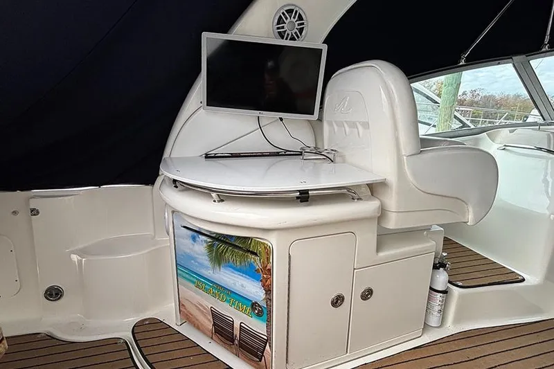 Slide: The Image of 2005 Sea Ray 340 Sundancer interior with TV, seating, and beach-themed decor. - 6
