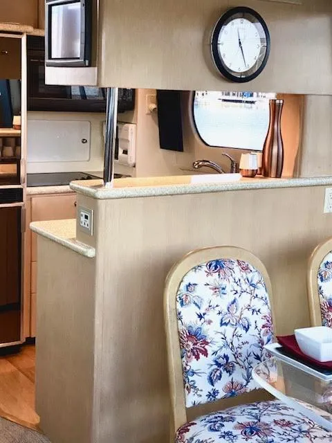 Slide: The Image of Interior of 1999 Carver 456 Aft Cabin Motor Yacht with floral chairs and kitchen area. - 25