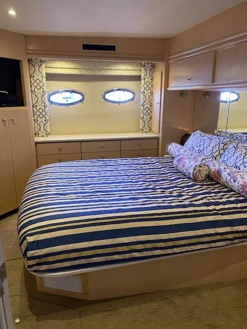 Slide: The Image of 1999 Carver 456 Aft Cabin Motor Yacht bedroom with striped bedding and porthole windows. - 33