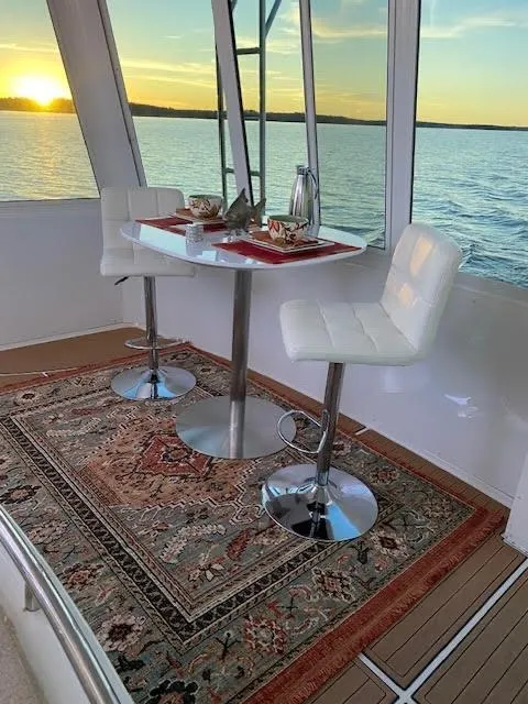 Slide: The Image of 1999 Carver 456 Aft Cabin Motor Yacht interior with elegant dining setup at sunset. - 36