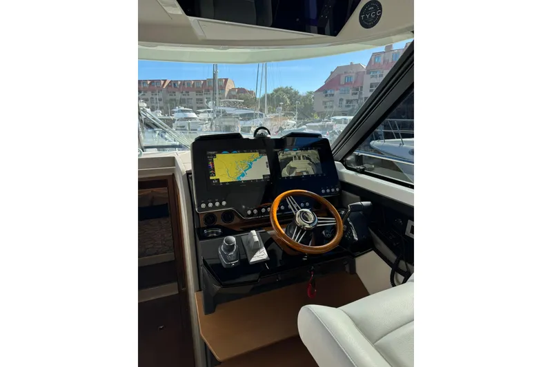 Slide: The Image of Helm of 2025 Tiara Yachts 43 LE with navigation screens and wooden steering wheel. - 27