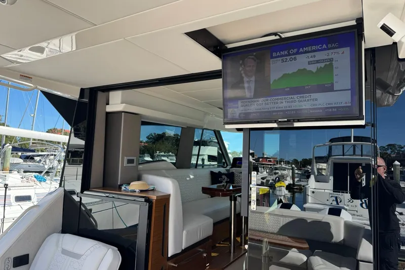 Slide: The Image of 2025 Tiara Yachts 43 LE interior with TV displaying financial news, docked at marina. - 72
