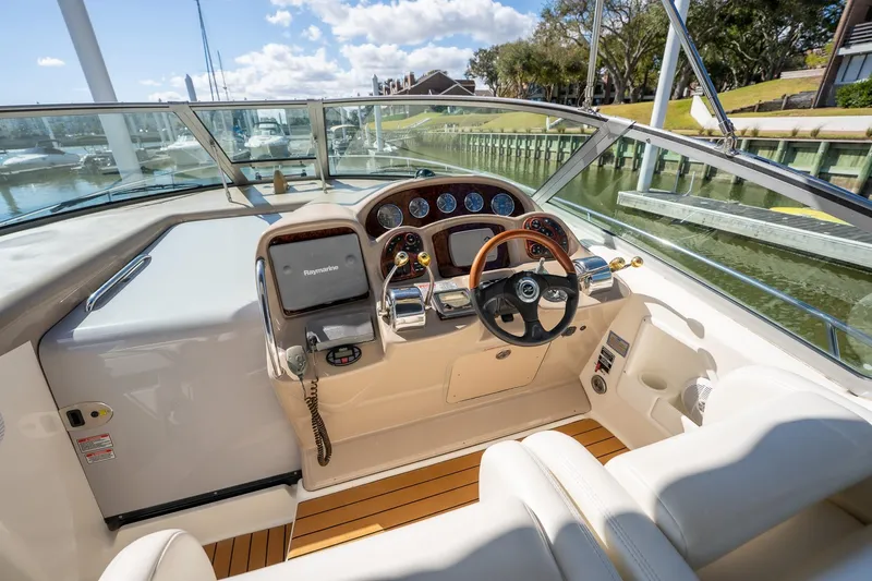 Slide: The Image of 2005 Sea Ray 340 Sundancer helm with Raymarine navigation, wood accents, and waterfront view. - 13
