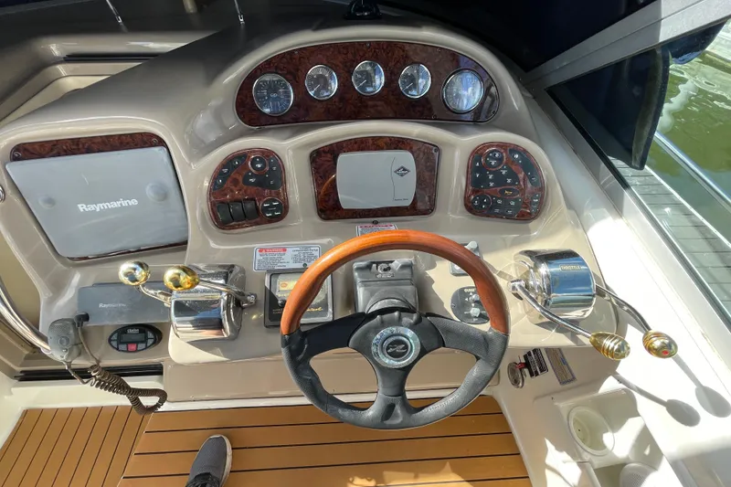 Slide: The Image of 2005 Sea Ray 340 Sundancer docked in a marina, surrounded by calm waters and other boats. - 19