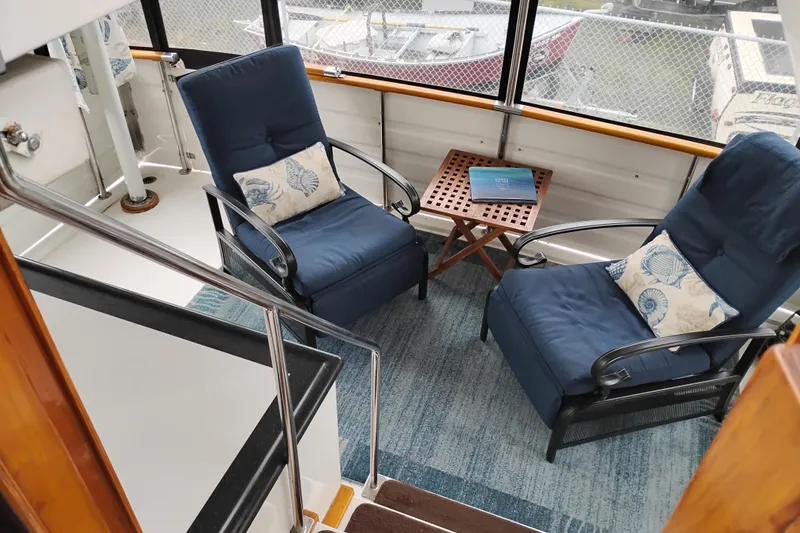 Slide: The Image of Cozy seating area on 1991 Jefferson 48 Rivanna Sundeck yacht with blue chairs and nautical decor. - 25