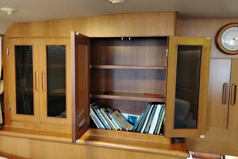 Slide: The Image of Wooden cabinet with open doors, revealing shelves and books inside a 1991 Jefferson 48 Rivanna Sundeck. - 31
