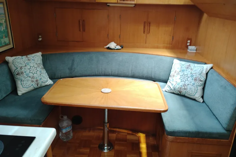 Slide: The Image of 1991 Jefferson 48 Rivanna Sundeck interior with wooden table, blue cushioned seating, and decorative pillows. - 41