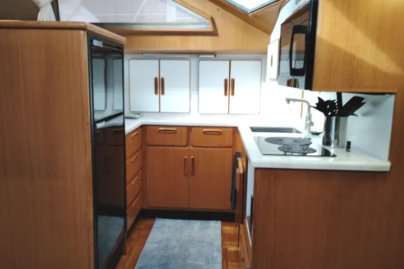 Slide: The Image of 1991 Jefferson 48 Rivanna Sundeck yacht kitchen with wood cabinetry and modern appliances. - 49