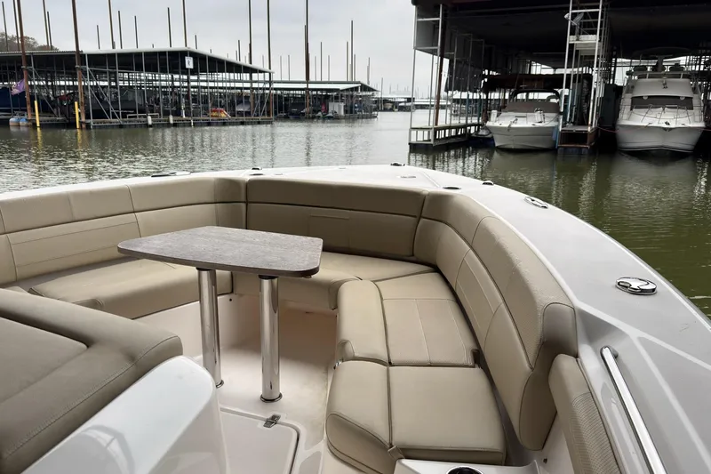 Slide: The Image of 2019 Pursuit S 408 Sport boat with beige seating and table, docked at marina. - 32