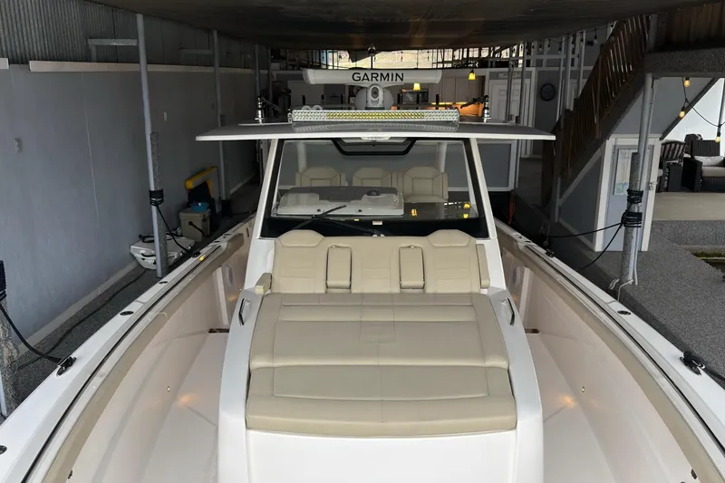 Slide: The Image of 2019 Pursuit S 408 Sport boat docked indoors with beige seating and Garmin equipment. - 36