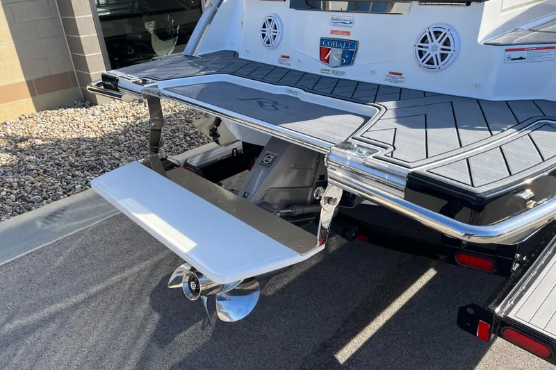 Slide: The Image of 2022 Cobalt R8 boat stern with swim platform and propeller, parked on gravel. - 7
