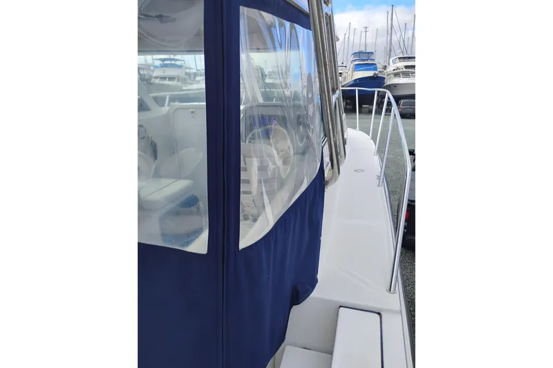 Slide: The Image of 2007 Glacier Bay 2685 Coastal Runner boat docked in marina, side view with blue canopy. - 11