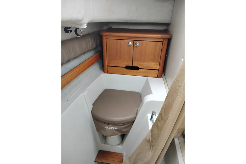 Slide: The Image of 2007 Glacier Bay 2685 Coastal Runner cabin interior with compact toilet and wooden cabinet. - 37