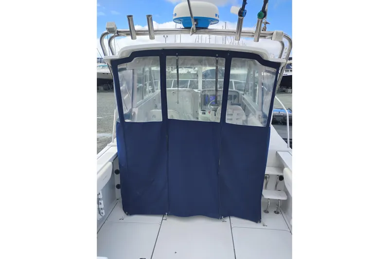 Slide: The Image of 2007 Glacier Bay 2685 Coastal Runner with blue canvas enclosure and fishing rod holders. - 8