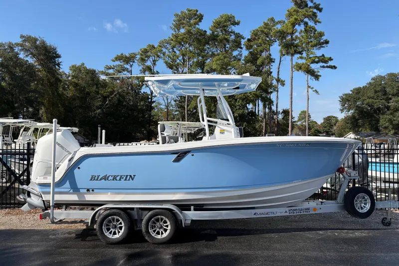 Slide: The Image of 2024 Blackfin 222CC boat on trailer, blue hull, parked outdoors. - 1