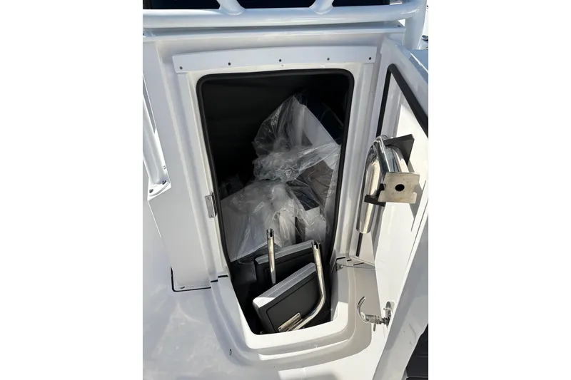 Slide: The Image of 2024 Blackfin 222CC storage compartment with stainless steel handle and interior items. - 14