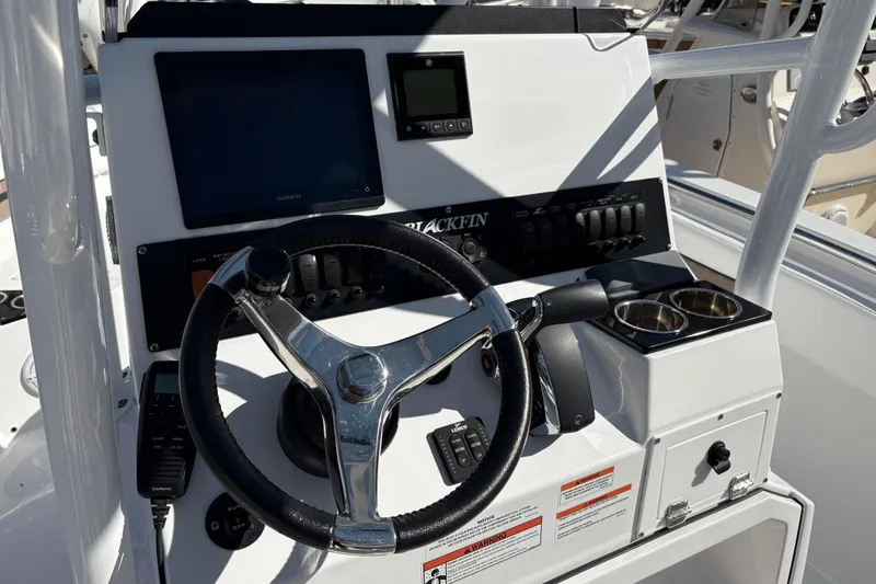 Slide: The Image of 2024 Blackfin 222CC boat console with steering wheel, controls, and cup holders. - 16