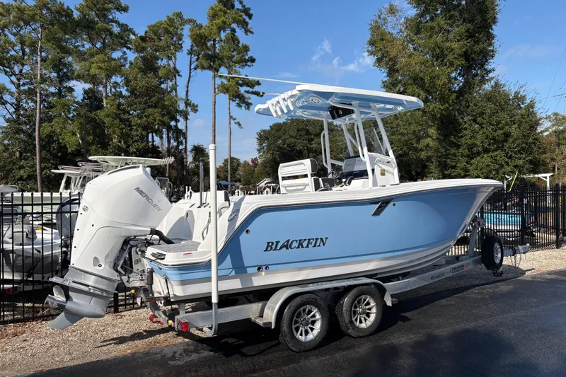 Slide: The Image of 2024 Blackfin 222CC boat on trailer, blue hull, parked outdoors. - 2
