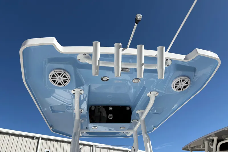 Slide: The Image of 2024 Blackfin 222CC boat's T-top with rod holders and speakers against blue sky. - 28