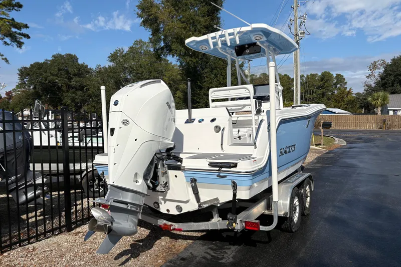 Slide: The Image of 2024 Blackfin 222CC boat on trailer, featuring a powerful outboard motor, parked outdoors. - 3