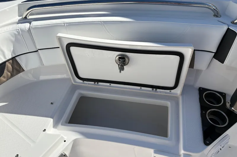 Slide: The Image of 2024 Blackfin 222CC boat storage compartment with open lid and cup holders. - 9