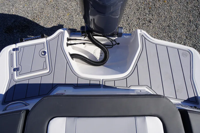 Slide: The Image of 2026 Chaparral 23 SSi OB boat deck with outboard motor, featuring sleek design and storage compartment. - 63