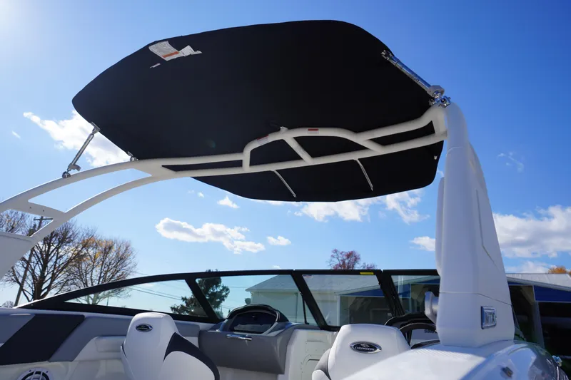 Slide: The Image of 2026 Chaparral 23 SSi OB boat with sleek black canopy under clear blue sky. - 68