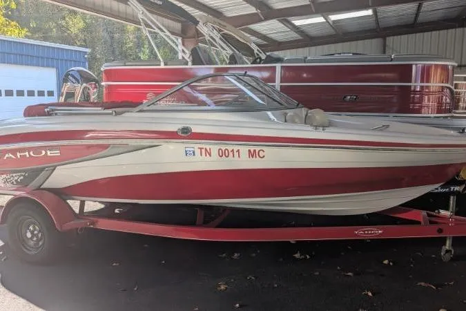 Slide: The Image of 2011 Tahoe Q5L I/O boat in red and white, parked in a covered area. - 3