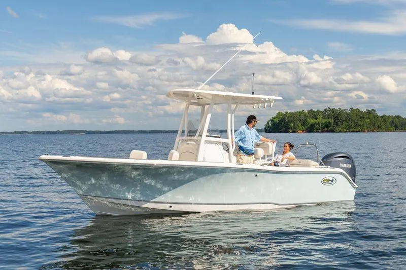 Slide: The Image of 2021 Sea Hunt Ultra 229 boat cruising on a calm lake under a cloudy sky. - 11