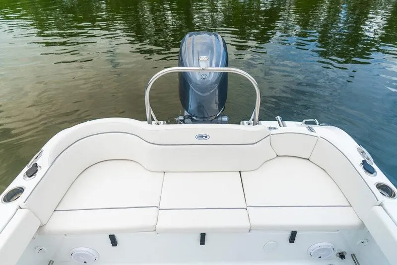Slide: The Image of 2021 Sea Hunt Ultra 229 boat with white seating and outboard motor on calm water. - 9
