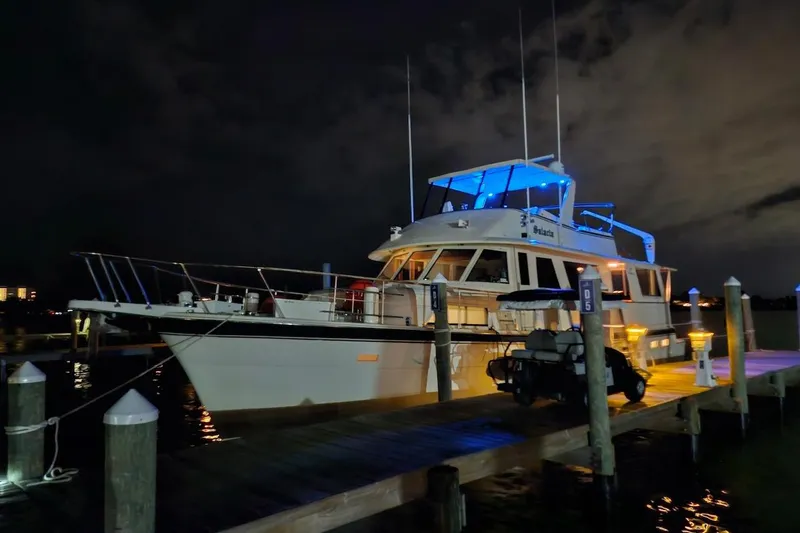 Slide: The Image of 1984 Hatteras 61 Cockpit MY yacht docked at night with vibrant lighting. - 23
