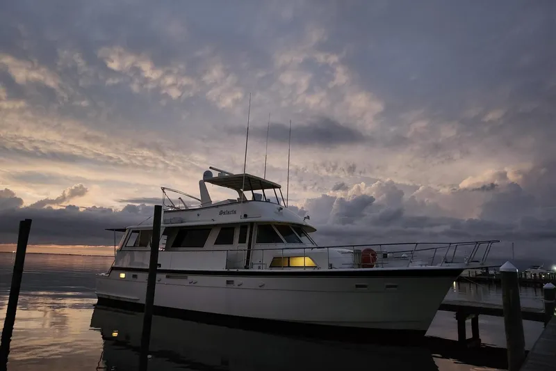 Slide: The Image of 1984 Hatteras 61 Cockpit MY yacht docked at sunset with blue lights. - 3