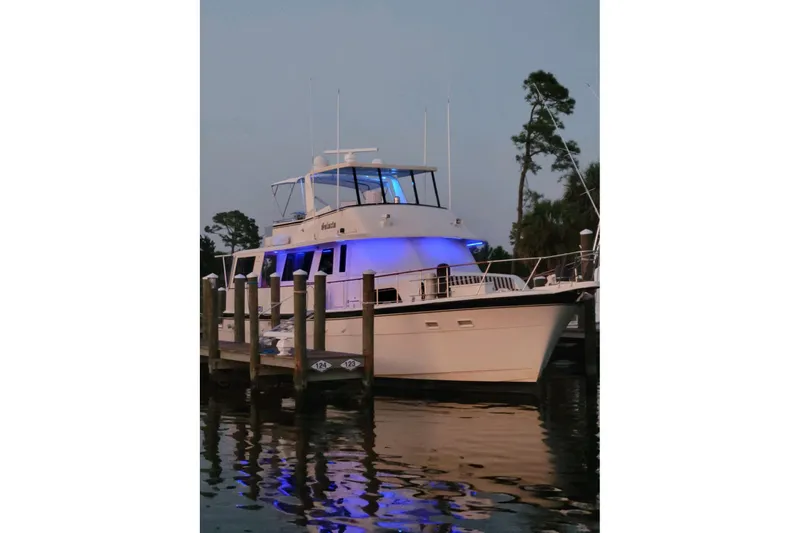 Slide: The Image of 1984 Hatteras 61 Cockpit MY yacht docked by trees and calm water. - 33