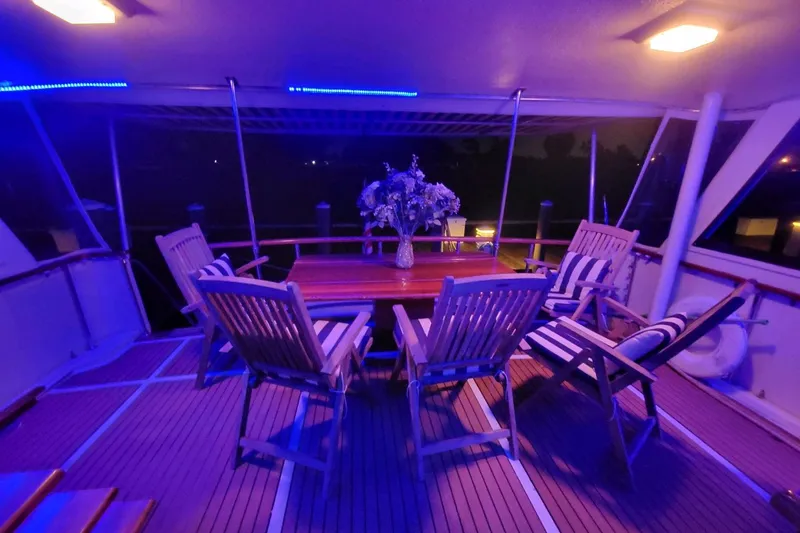 Slide: The Image of Aboard 1984 Hatteras 61 Cockpit MY, elegant dining area with floral centerpiece overlooking serene waters. - 7